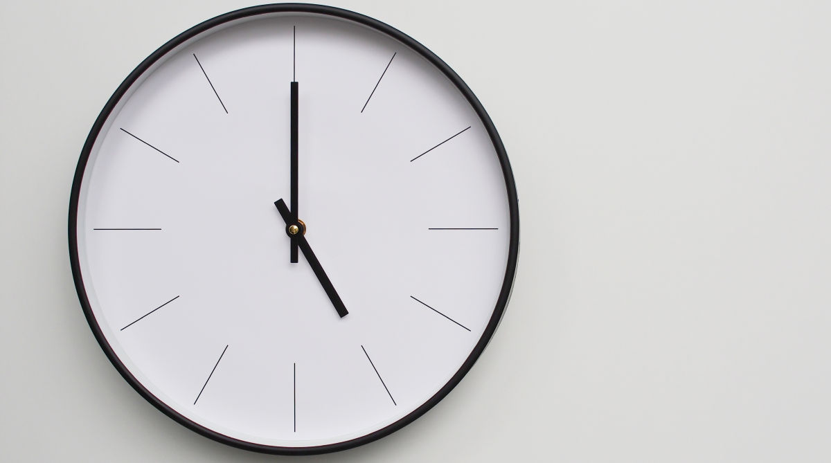 Zegar umieszczony na ścianie, otoczony białym tłem
